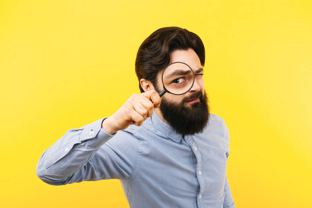 bearded man with magnifier over yellow  background, search concept - Photo, Image