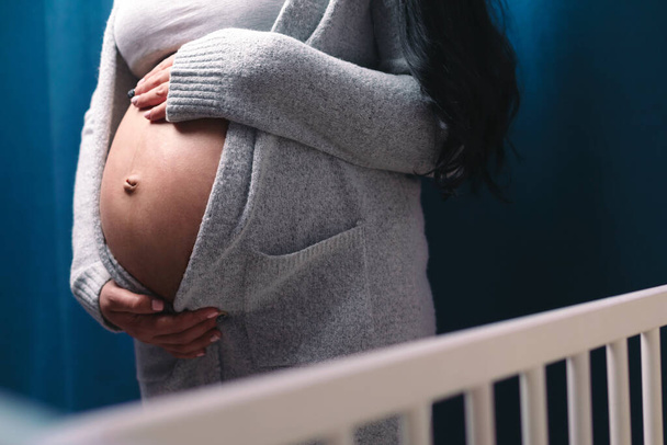 giovane donna incinta toccando la pancia su sfondo blu, concetto di attesa del bambino - Foto, immagini