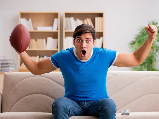 Mies katsomassa jalkapalloa kotona istuu sohvalla - Valokuva, kuva