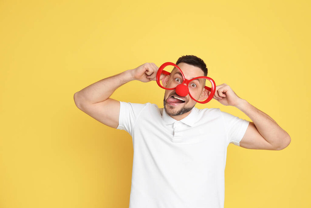 Funny man with clown nose and large glasses on yellow background. April fool's day - Foto, Bild