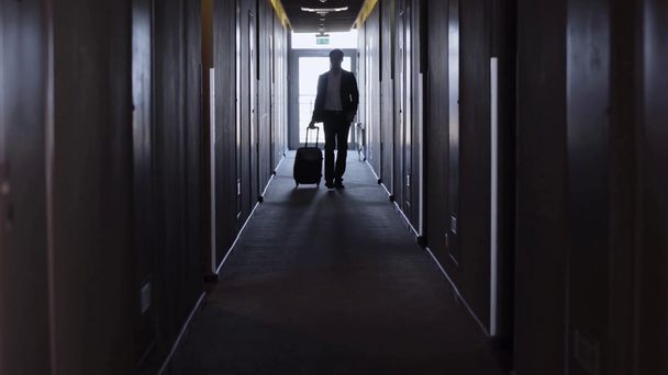 επιχειρηματίας με βαλίτσα με τα πόδια κατά μήκος του διαδρόμου του ξενοδοχείου - Πλάνα, βίντεο