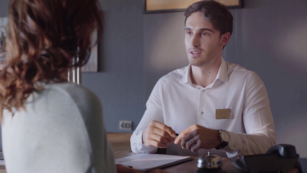 usmívající se hotelová recepční mluví a dává kartu ženě  - Záběry, video