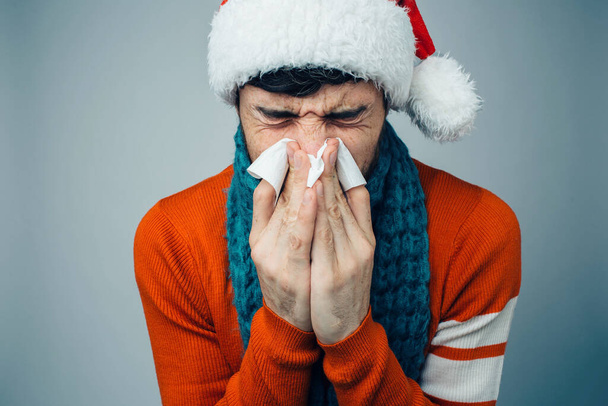 Young bearded man isolated over background. Sick ill person sneezing into white napkin. Flu or influenza. Sickness time. Suffer from nose running. - 写真・画像