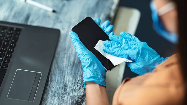 Donna in quarantena indossa guanti blu telefono di pulizia
 - Foto, immagini