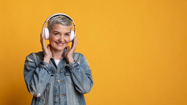 Music lover. Portrait of smiling mature woman in wireless headphones - Photo, image