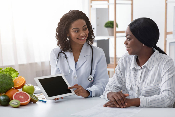 amichevole dietologo mostrando nero signora paziente vuoto digitale tablet schermo
 - Foto, immagini