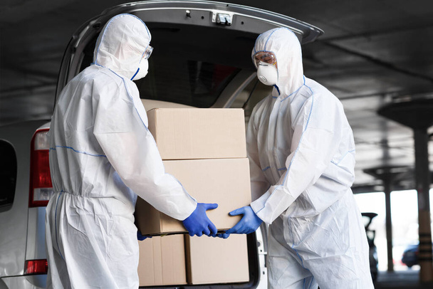 コロナウイルスのハズマットスーツの労働者は薬を運ぶ - 写真・画像