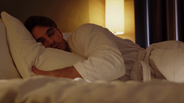 oppervlakte niveau van de jonge man slapen in bed in hotelkamer - Video