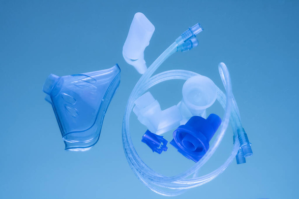 Mask for inhaler for pneumonia with sprayer and container on a blue mirror medical background - Φωτογραφία, εικόνα