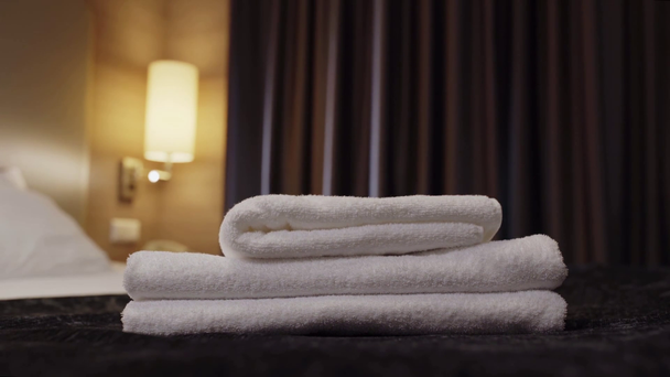 清潔なテリータオルをベッドの上のホテルの部屋に置くメイドのクロップドビュー - 映像、動画