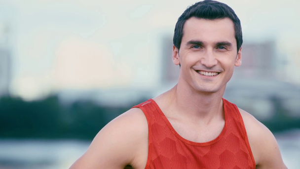 schöner, junger Sportler, der auf der Brücke in die Kamera lächelt - Filmmaterial, Video