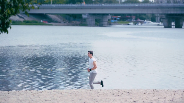 Nehir kenarında koşan genç sporcunun yan görüntüsü  - Video, Çekim