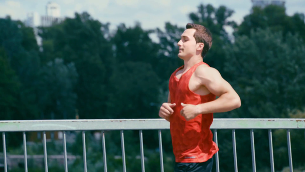 jonge sportman die over de brug rent en stopt om uit te rusten - Video