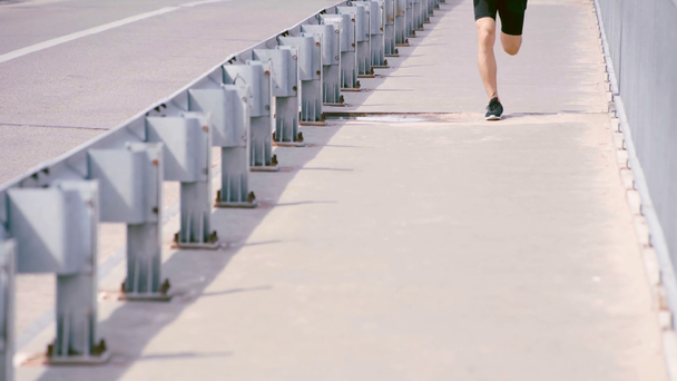 bijgesneden beeld van sportman loopt op asfalt weg - Video