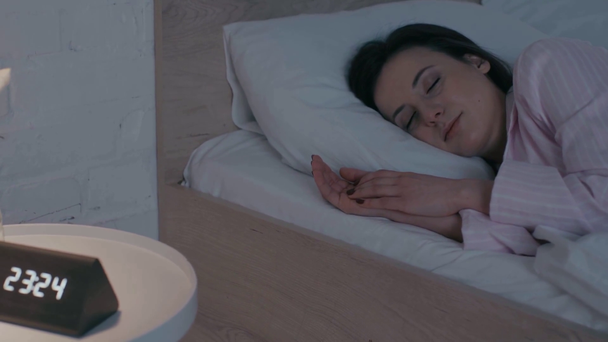 Focus selettivo di donna che dorme sul letto vicino all'orologio e fiore sul comodino
 - Filmati, video