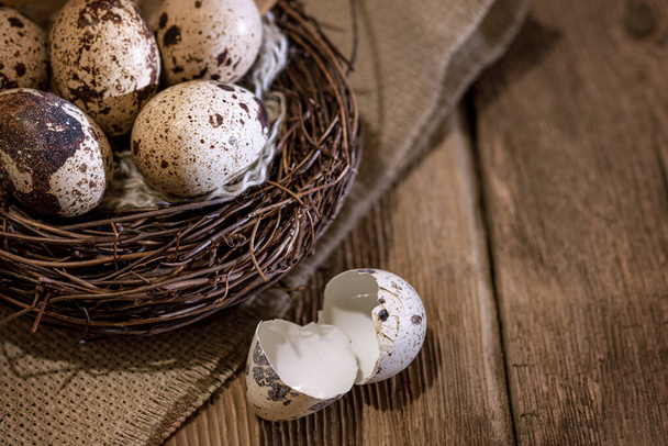 nest with quail eggs on the background of burlap and an old wooden table, rustic still life, Easter - Foto, Imagem