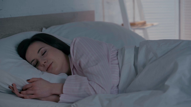Woman sleeping while turning off light in bedroom - Кадри, відео