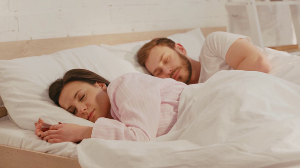 Enfoque selectivo de pareja joven durmiendo en la cama por la mañana
 - Metraje, vídeo