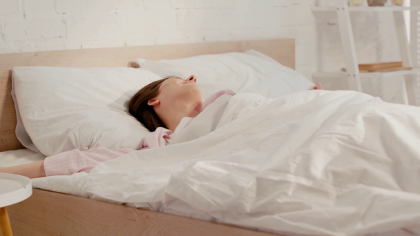 Glimlachende vrouw die 's morgens wakker wordt in bed - Video
