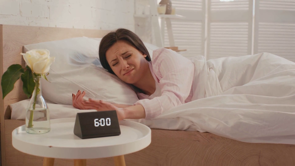 Αγχωμένη γυναίκα ξυπνάει και κλείνει το ξυπνητήρι στο κρεβάτι το πρωί  - Πλάνα, βίντεο