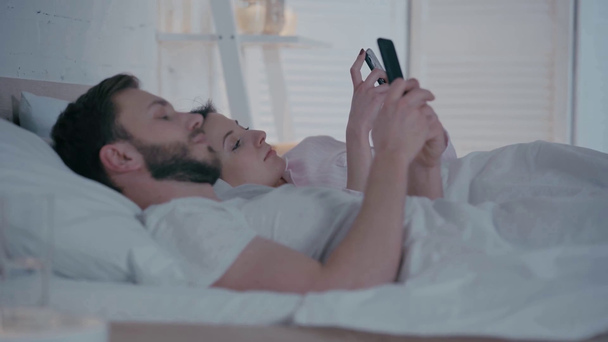 Selektiver Fokus von Paaren mit Smartphones im Bett  - Filmmaterial, Video