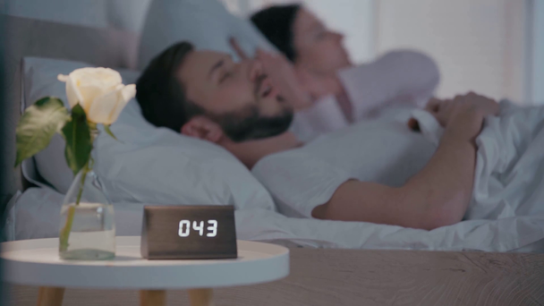 Selective focus of tired woman suffering from snoring man near clock on table - Metraje, vídeo
