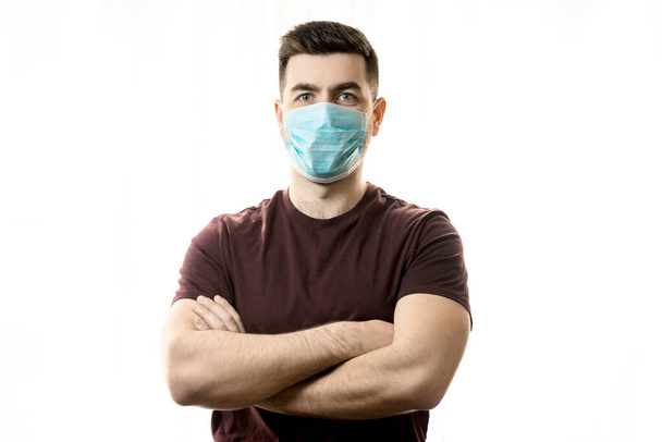 コロナウイルスと安全のテーマ。ウイルスの青いマスクをした若い男. - 写真・画像
