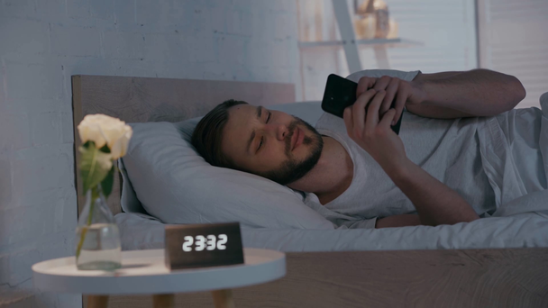 Szelektív fókusz a férfi használ okostelefon az ágyban éjszaka - Felvétel, videó
