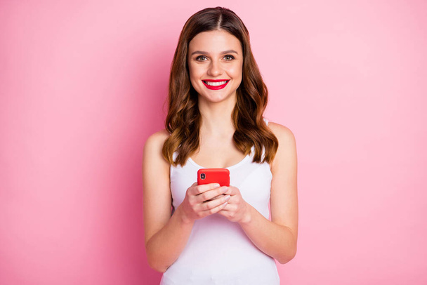 Muotokuva positiivinen iloinen tyttö käyttää matkapuhelinta nauttia lukemisesta sosiaalinen verkosto uutuus kulumista tyylikäs trendikäs singlet eristetty vaaleanpunainen väri tausta
 - Valokuva, kuva