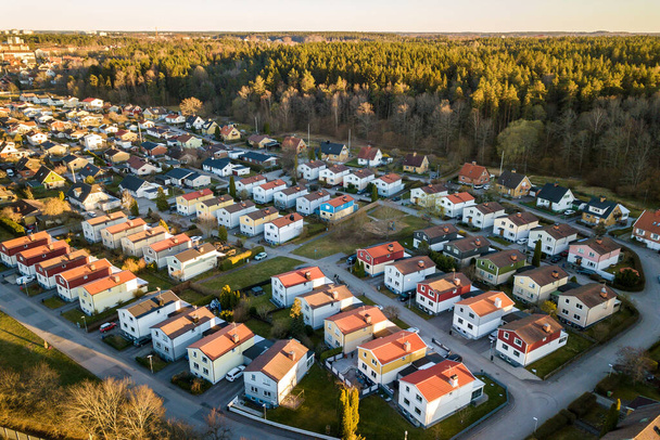 Luftaufnahme von Wohnhäusern mit roten Dächern und Straßen mit geparkten Autos im ländlichen Stadtgebiet. Ruhige Vororte einer modernen europäischen Stadt. - Foto, Bild