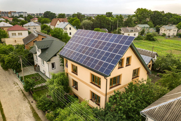 Vista superior aérea da nova casa de campo residencial moderna com azul brilhante sistema de painéis solares fotovoltaicos no telhado. Conceito de produção de energia verde ecológica renovável. - Foto, Imagem