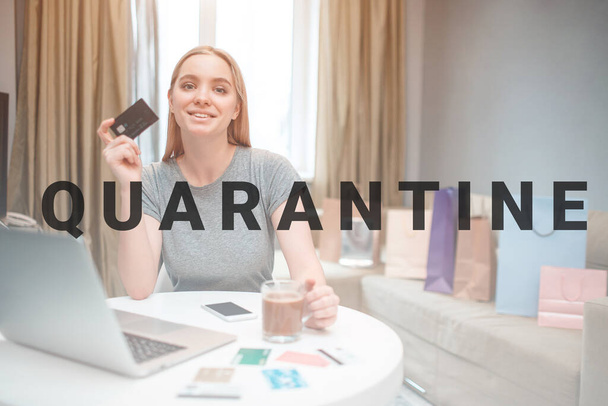 Online shopping at home. Young happy woman is ready to spend money from payment card on black Friday while sitting at the table - Foto, afbeelding