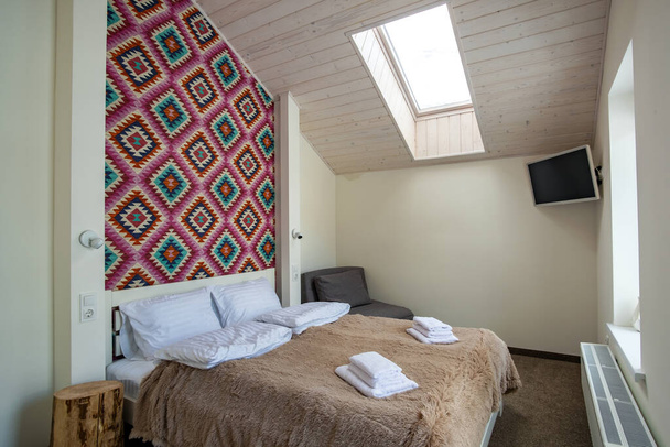 Çatı katında geniş bir otel odasının içinde büyük bir çift kişilik yatağın üzerinde temiz çarşaflar. Modern bir evdeki modern Mansard odası.. - Fotoğraf, Görsel