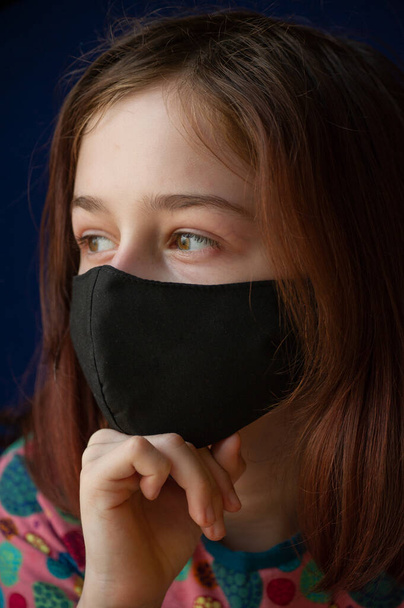 Tyttö hengitysteiden mustassa naamiossa. Sepelvaltimovirus, sinitaustainen naamiotyttö. Otsikko koronaviruksen puhkeamisesta Kiinassa, sairaus. Epidemia. Teini-ikäinen, sepelvaltimovirus. Virusta. Naamio
 - Valokuva, kuva