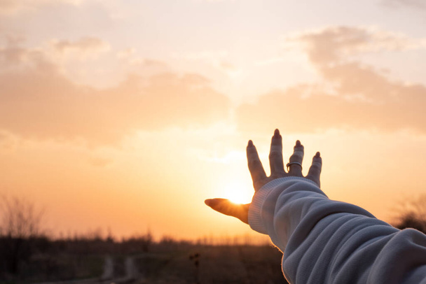 Photo of a female hand reaching amazing sunset, beautiful nature - Photo, Image