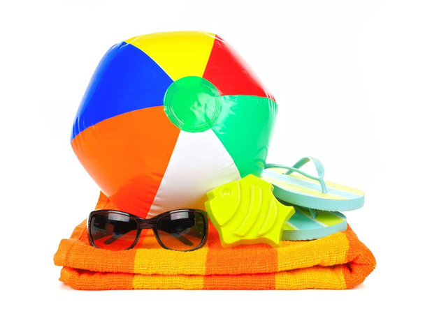 Balle de plage, lunettes de soleil et tongs sur serviette orange isolée sur blanc
 - Photo, image