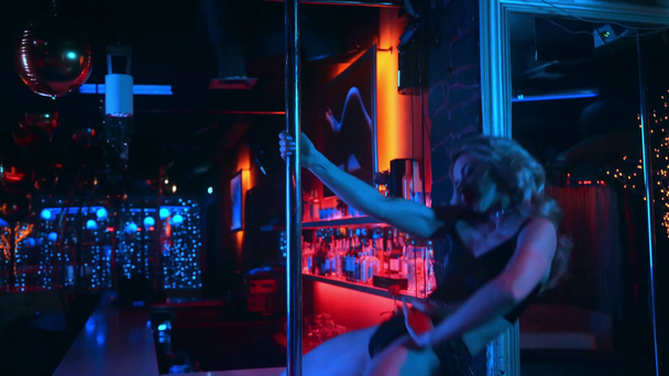 стриптизерша на каблуках танцует возле пилона в стрип-клубе
  - Кадры, видео