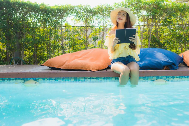 Portret młoda azjatycka kobieta czytać książki wokół odkryty basen w ośrodku hotelowym - Zdjęcie, obraz