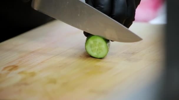 The cook cuts the cucumber with a sharp knife on a cutting board - Footage, Video