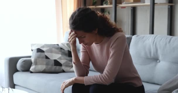 Worried upset young woman sitting on sofa suffering from stress - Footage, Video
