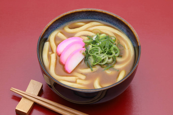 Japán curry udon tészta egy tálban evőpálcikákkal az asztalon - Fotó, kép