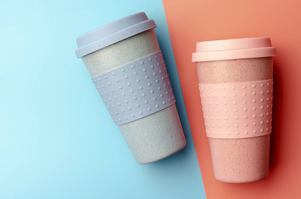 Reusable bamboo coffee cup with silicone holder on colorful background - Foto, Imagem