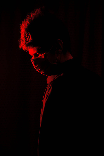 μασκοφόρος γιατρός σε σκοτεινό δωμάτιο με κόκκινο φως - Φωτογραφία, εικόνα