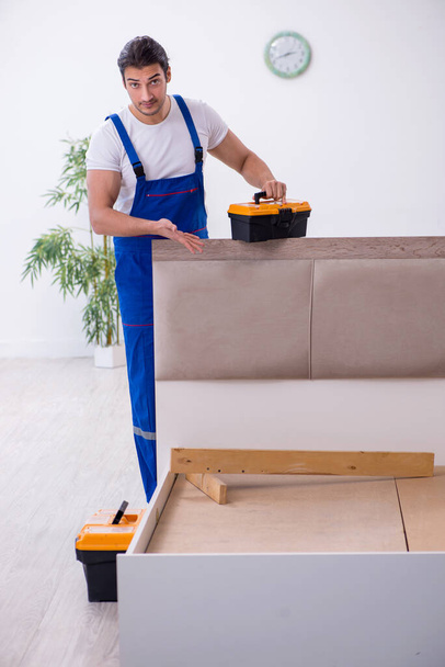 Nuori mies urakoitsija asentamassa huonekaluja kotona - Valokuva, kuva