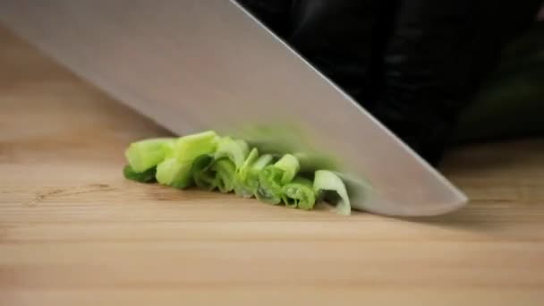 The cook cuts green onions with a sharp knife on a cutting board - Footage, Video