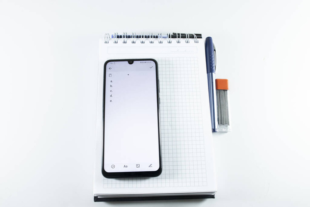 Concept of notepad phone pen. The photo was taken on white background and studio. - Foto, Imagem
