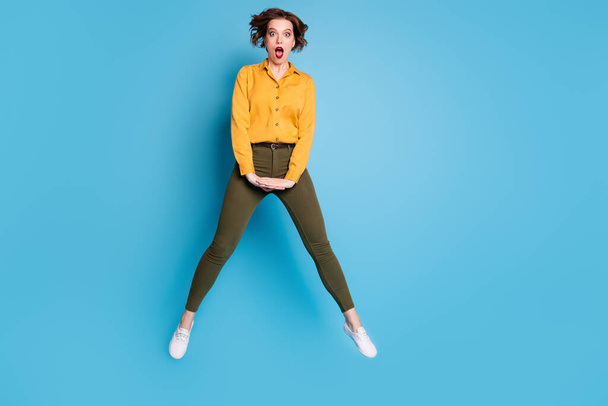 Full length photo of pretty business lady jumping high up open mouth not believe boss promoted her wear yellow shirt green pants footwear isolated bright blue color background - Foto, Bild