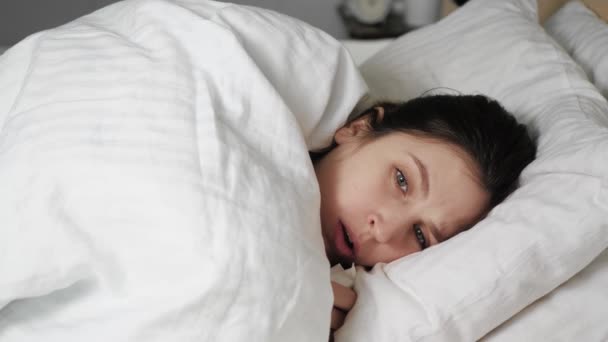 Coughs woman caucasian woman lies in bed covered with blanket intopaper napkin. Cold, flu, laryngitis, tuberculosis, asthma, coronavirus, bronchitis, allergies, pneumonia concepts. Close up - Πλάνα, βίντεο