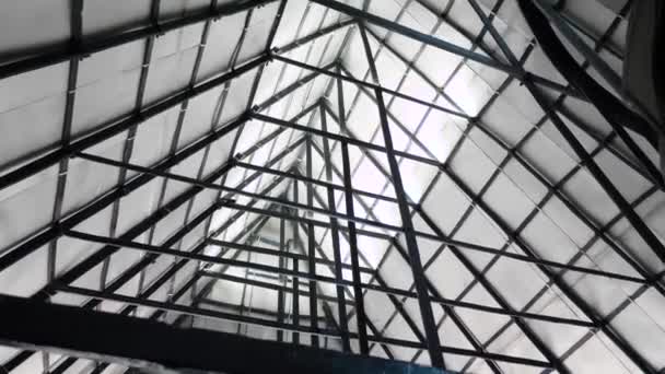 Triangular roof with iron beams. Stock footage. Bottom view of metal structure of triangular roof with many beams. Under triangular arch of metal structure - Footage, Video