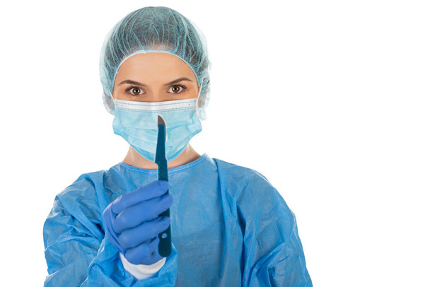 Young female surgeon with sterile uniform is holding a scalpel on isolated background - Zdjęcie, obraz